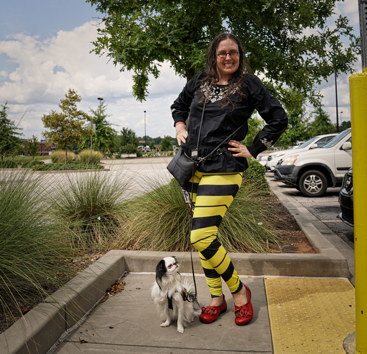Veronica wearing black and yellow striped leggings and a black long sleeved shirt,and red shoes. Hestia is wearing her Hufflepuff vest. Veronica is posing with her left leg out.