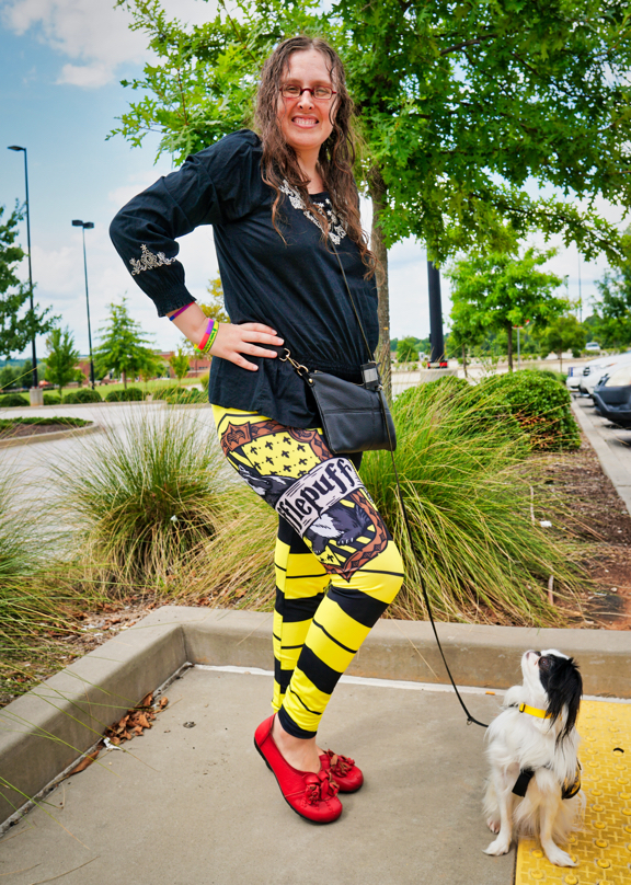 Veronica holding her right leg out, this leg of the leggings has the Hufflepuff crest on it! Hestia is watching Veronica closely!