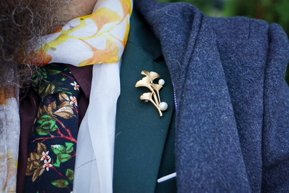 A closeup of Brad's ginkgo brooch, it is gold with two pearls on it.