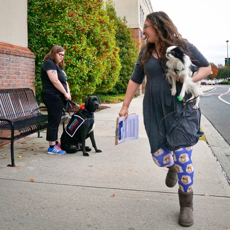 Veronica carrying Hestia runs past Kristi with Jax.