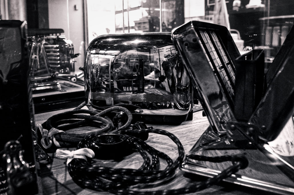 A black and white picture of many chrome toasters, with lots of interesting things reflecting in their surfaces.