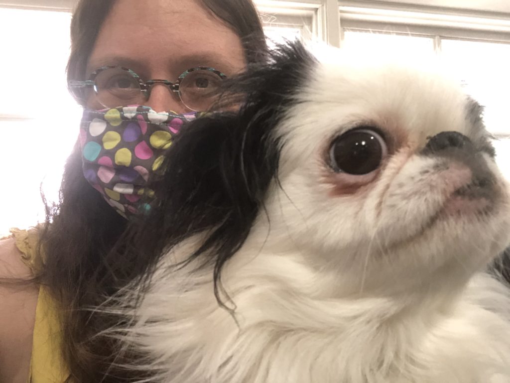 Veronica wearing a mask with multicolored polka dots on it with Hestia's face in the foreground. This picture was taken in the waiting room.